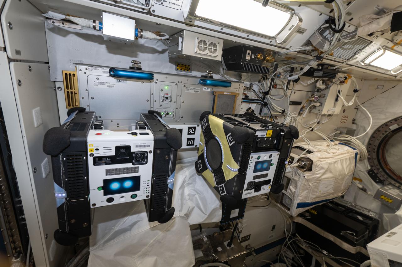 Two Astrobee free-flying robots at their docking station inside the Kibo module