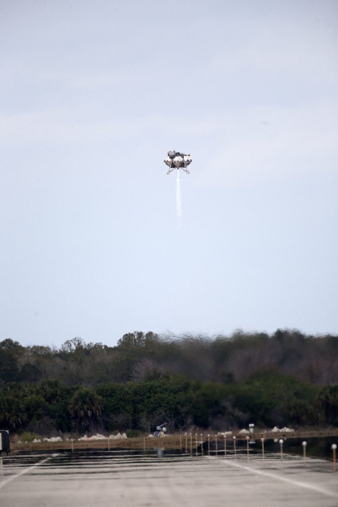Small lander far off in a pale sky, a thin white exhaust plume trailing below
