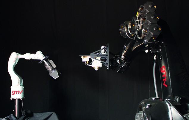 Two robot arms facing each other in GMV&rsquo;s darkened platform-art hall during EROSS+ testing