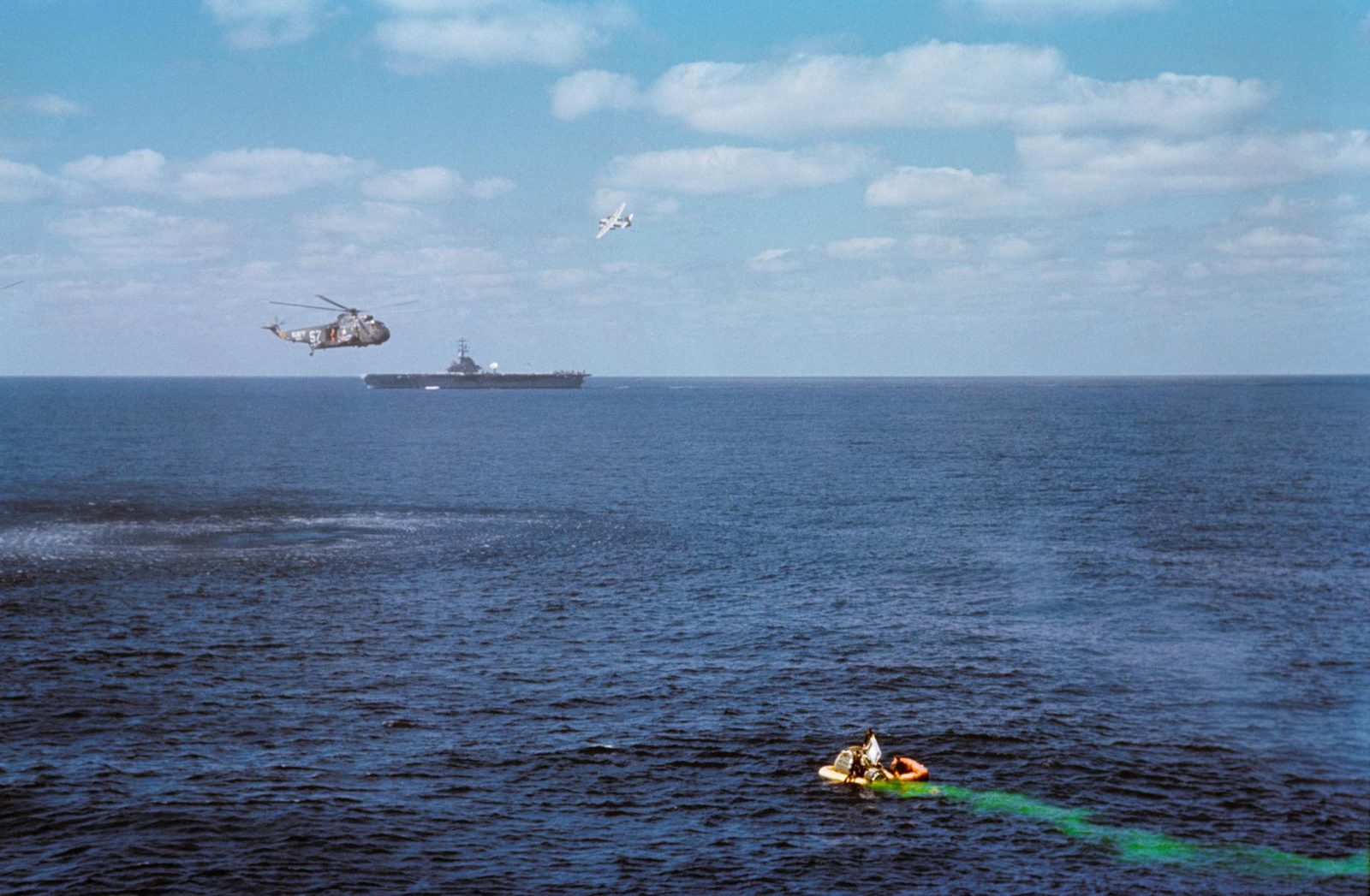 A recovery helicopter hovers over a Gemini spacecraft floating in the Atlantic